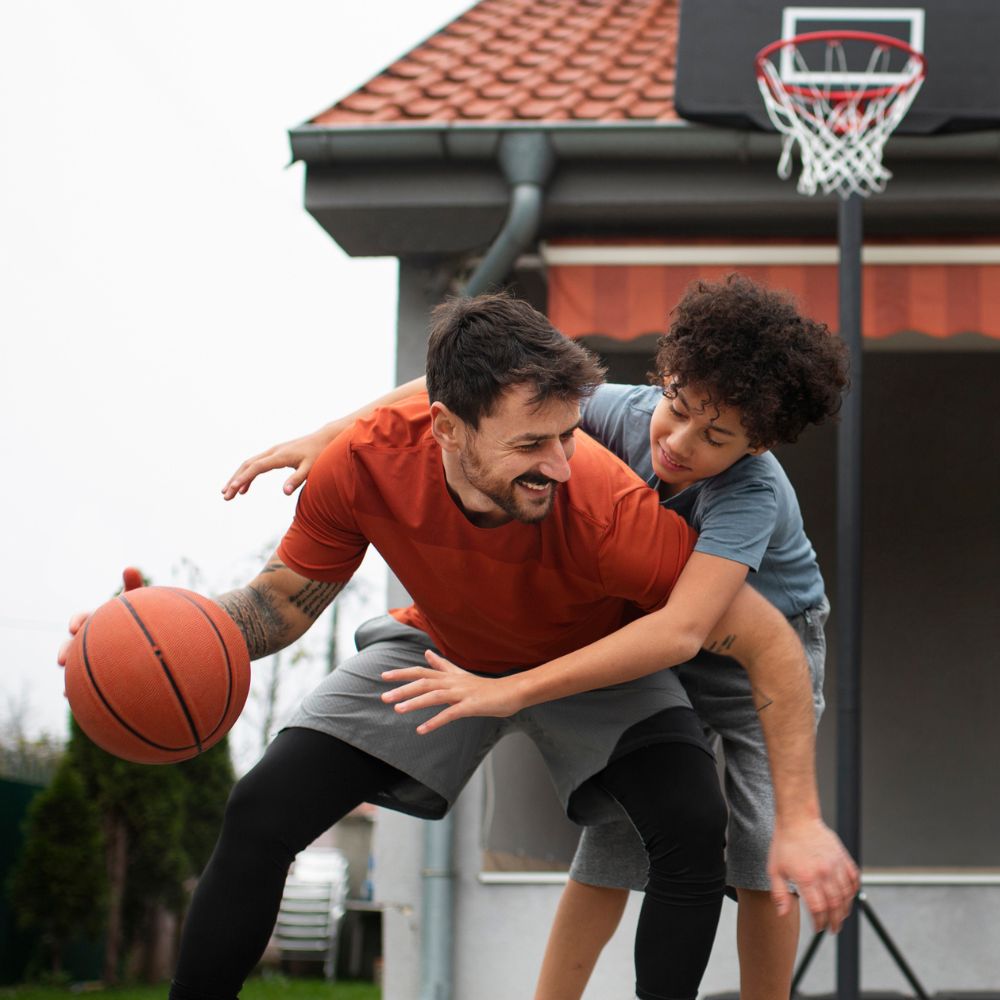 Man playing basketball with a child in front of a house

