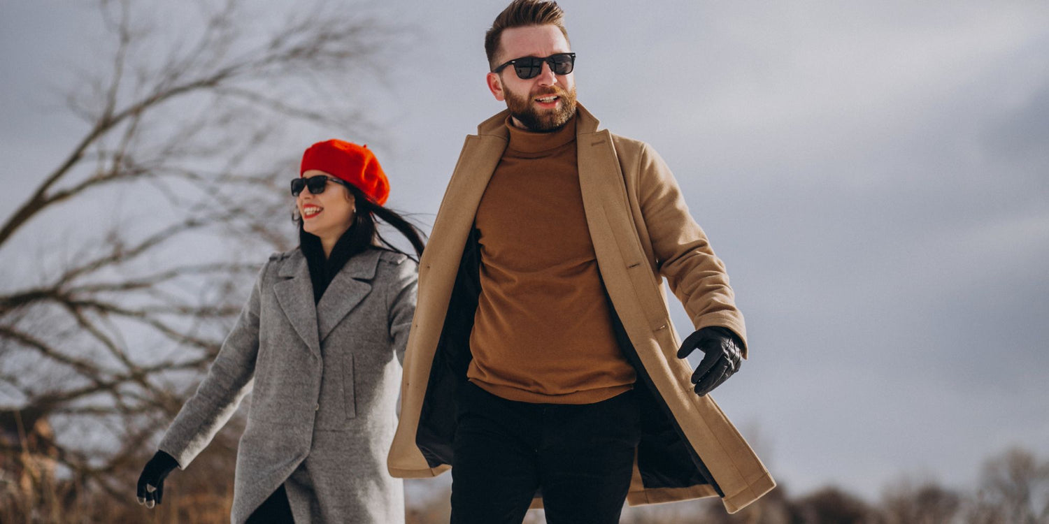 Two people walking outdoors in winter clothing with a cloudy sky.

